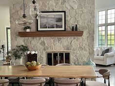 a dining room table surrounded by chairs and a fire place in front of a stone wall