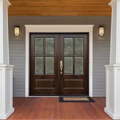 the front door of a house with two lights on each side and an entrance mat