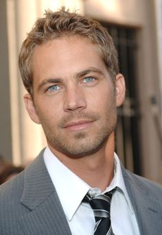 a close up of a person in a suit and tie looking at the camera with blue eyes