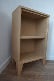 a wooden shelf sitting on top of a hard wood floor next to a white wall