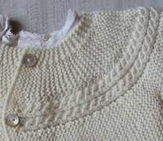 a white knitted sweater with buttons on it