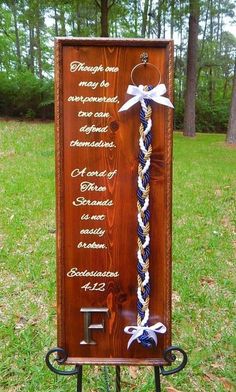 a wooden plaque with white and blue ribbons attached to it in front of some grass