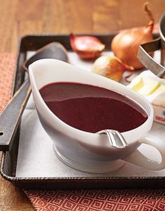 a bowl of soup on a tray next to an onion and cheese dish with a measuring spoon