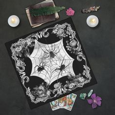 a table topped with candles and cards next to a spider web design on black paper