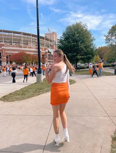 a girl in an orange miniskirt walking down the street