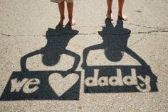 two people are standing on the sidewalk with their shadow in front of them that says we love daddy