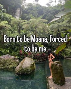 a woman sitting on the edge of a pool in front of some rocks and trees