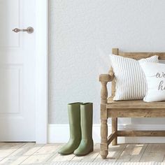 a wooden bench sitting next to a pair of green boots on top of a hard wood floor