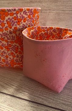 two pink and orange bags sitting on top of a wooden table next to each other