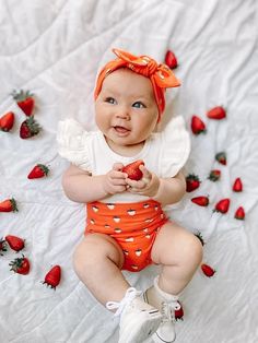 a baby sitting on top of a bed with strawberries all over it's body