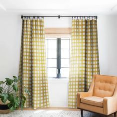 a chair sitting in front of a window next to a potted plant on top of a rug