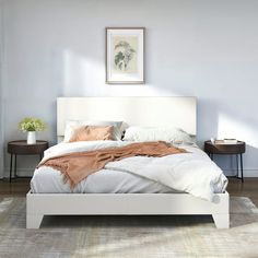 a white bed sitting in a bedroom on top of a hard wood floor