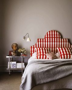 a bed with red and white bedspread next to a lamp on a table