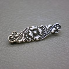 This small 800 silver brooch is an authentic Yogya  (also known as Jogya or Djokja) Yogyakarta repousse silverwork from Java Indonesia, handcrafted in 1930's. This dainty bar brooch is featuring a beautifully stylized flower ornament. A lovely piece of Asian Art Deco jewelry with lots of character! The brooch will be shipped in a gift box. The brooch measures 1 2/5 inches long by 2/5 inches wide  (3.5 cm x 1 cm)  Weight: 3.2 grams Roll-over clasp closure The brooch is hallmarked for 800 silver, Silver Art Nouveau Jewelry For Ceremonial Occasions, Art Nouveau Silver Jewelry For Ceremonial Occasions, Elegant Engraved Brooches For Ceremonial Occasions, Vintage Antique Silver Sterling Silver Brooches, Silver Art Nouveau Brooch, Art Nouveau Silver Brooch, Classic Engraved Brooches For Wedding, Classic Engraved Wedding Brooches, Silver Art Nouveau Brooches For Gifts