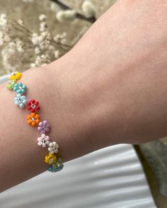 a person's arm with a bracelet made out of small beads and flowers on it