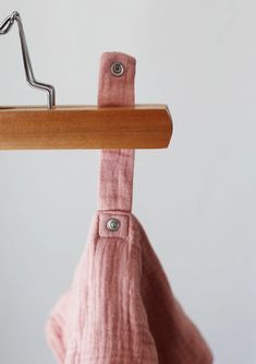 a pink bag hanging from a wooden hanger with clothes pins on the top and bottom