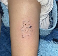 a small teddy bear tattoo on the right arm and leg, with a tiny outline