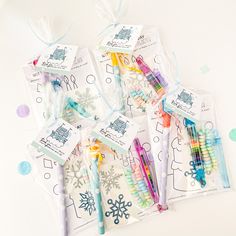 several different colored pens in plastic bags on a white surface with confetti and snowflakes