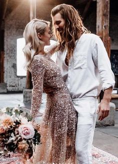 a man and woman standing next to each other in front of a rug with flowers on it