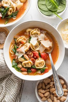 three bowls filled with pasta, spinach and other foods on top of a table