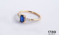 a gold ring with an oval blue stone and two small white stones on the side