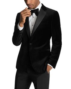 a man in a tuxedo is adjusting his bow tie