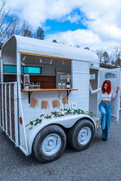 a woman standing in front of a trailer with plants growing out of the back door