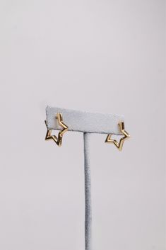 two star shaped earrings on top of a white stand