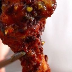 a person holding up a piece of meat with sauce on it