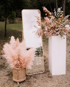 there is a vase with flowers and a mirror on the ground next to each other