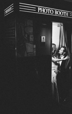 black and white photograph of a man kissing a woman in a train car with the words photo booth on it