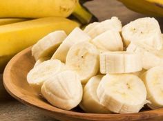 a wooden bowl filled with sliced bananas on top of a table