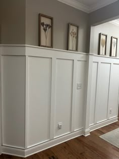 a room with white paneling and pictures on the wall