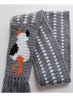 two crocheted gray and white scarfs with an orange cat on the front