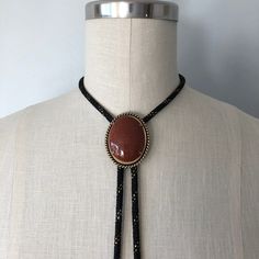 A lovely vintage bolo in perfect condition! Great gift for someone this holiday season! Introduction to Goldstone: Here's some good advice 🪶 Keep calm and carry the Goldstone crystal to ensure a golden future. Because let's be realistic--the mysterious abyss of the unknown--also known as the future--can be a daunting aspect. Known as the 'ambition' stone, the Goldstone crystal meaning is linked with boosting your drive and confidence, the essential mindset for paving the way for all your dreams 70s Jewelry Necklaces, Western Style Gold Lariat Jewelry, Vintage Lariat Jewelry With Sliding Knot, Gold Adjustable Cord Bolo Ties For Gift, Adjustable Antique Necklaces For Festivals, Antique Adjustable Necklaces For Festivals, Antique Adjustable Necklace For Festivals, Vintage Brown Jewelry With Adjustable Cord, Gold Lariat Bolo Tie With Adjustable Length