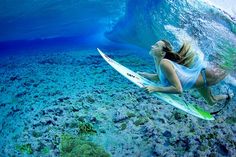 a woman riding a surfboard on top of a wave in the ocean under water