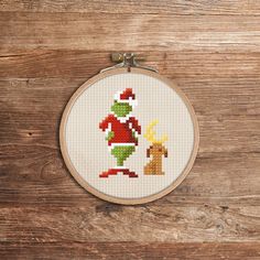 a cross stitch christmas ornament on a wooden surface