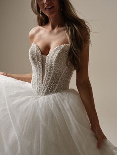 a woman in a wedding dress posing for the camera with her hand on her hip