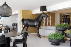 a statue of a horse stands in the middle of a room with chairs and tables