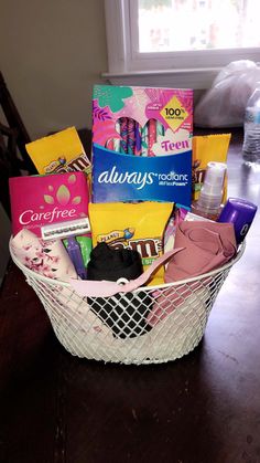 a white basket filled with lots of different items on top of a wooden table next to a window