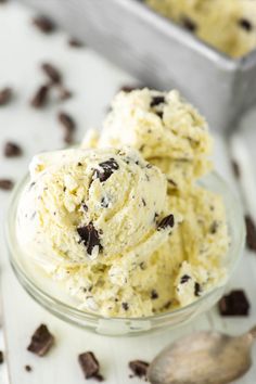 two scoops of ice cream in a glass bowl with chocolate chips on the side