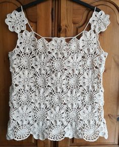 a white crocheted top hanging on a wooden door