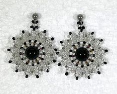 two pairs of black and white beaded earrings on a white surface with beads in the center