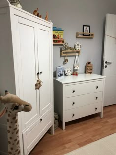 a bedroom with two white dressers and a stuffed giraffe