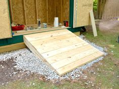 the back of a house being built with wooden boards and plywood on the ground