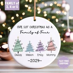 personalized christmas ornament with family names and trees on it in front of a christmas tree