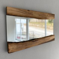 a mirror mounted to the side of a wall next to a white wall and window