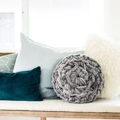 several pillows on a bench in front of a window with white and blue accents,