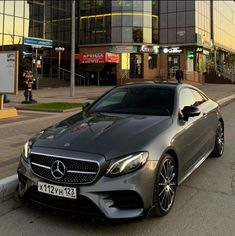 a mercedes benz coupe parked on the side of the road in front of a building