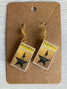 a pair of earrings with the words playbill on it and a star hanging from them